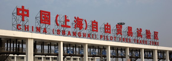 A man, right, speaks to a motorbike taxi driver in front of the gate to China (Shanghai) Pilot Free Trade Zone's Pudong free trade zone in Shanghai, China, on Thursday, Oct. 24, 2013. The area is a testing ground for free-market policies that Premier Li Keqiang has signaled he may later implement more broadly in the world's second-largest economy. Photographer: Tomohiro Ohsumi/Bloomberg via Getty Images